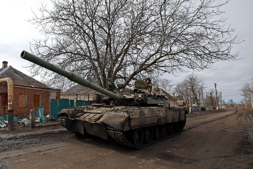 An Ukrainian servicemen gestures as he rides a tank om a road towards the frontline town of Bakhmut in Chasiv Yar