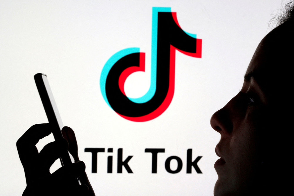 FILE PHOTO: A person holds a smartphone as Tik Tok logo is displayed behind in this picture illustration