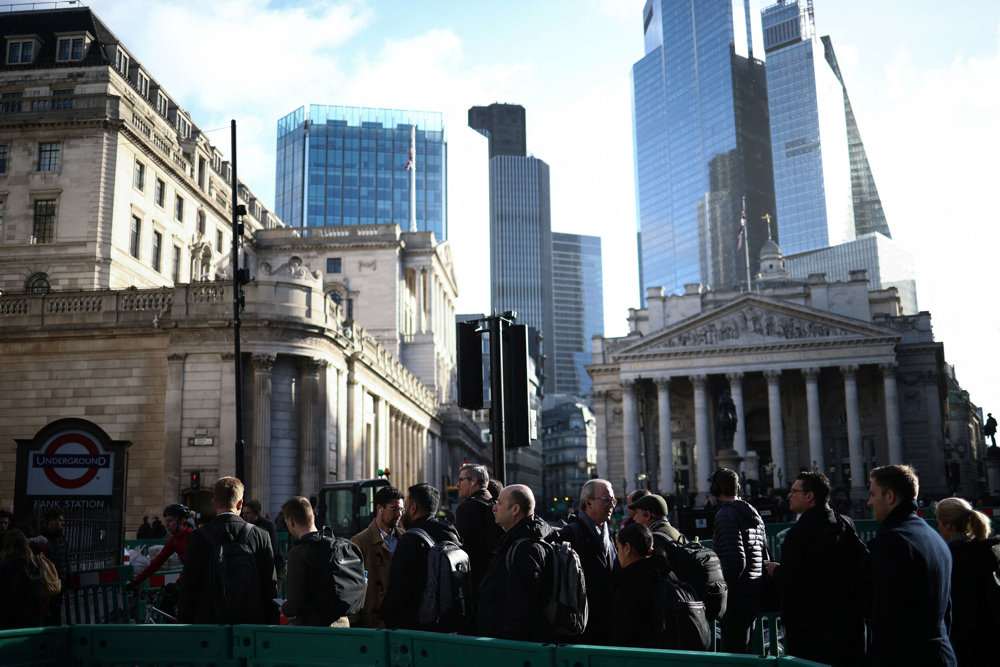 People walk outside the Bank of England in the City of London financial district in London