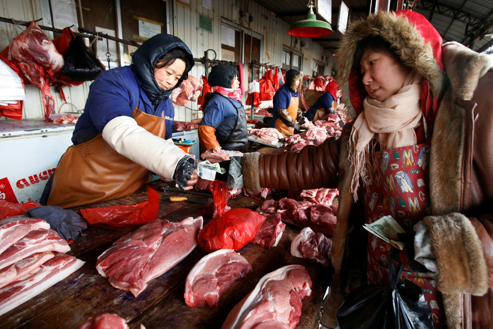 FILE PHOTO: A customer buys pork at a market in Beijing