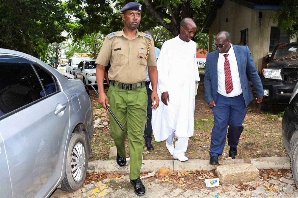 Detectives escort Ezekiel Ombok Odero at the police headquarters in Mombasa