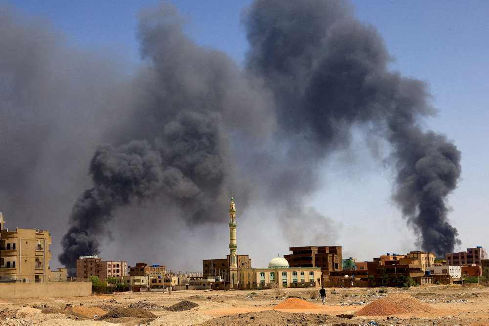 FILE PHOTO: Man walks while smoke rises above buildings after aerial bombardment in Khartoum North