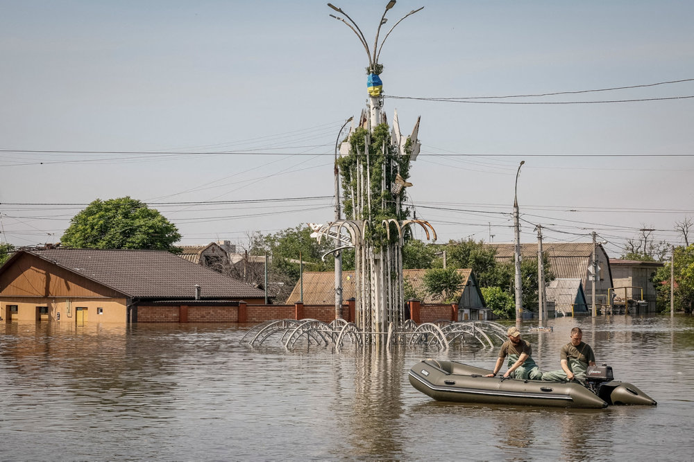 Volunteers sail on a boat during an evacuation of local residents from a flooded area after the Nova Kakhovka dam breached in Kherson