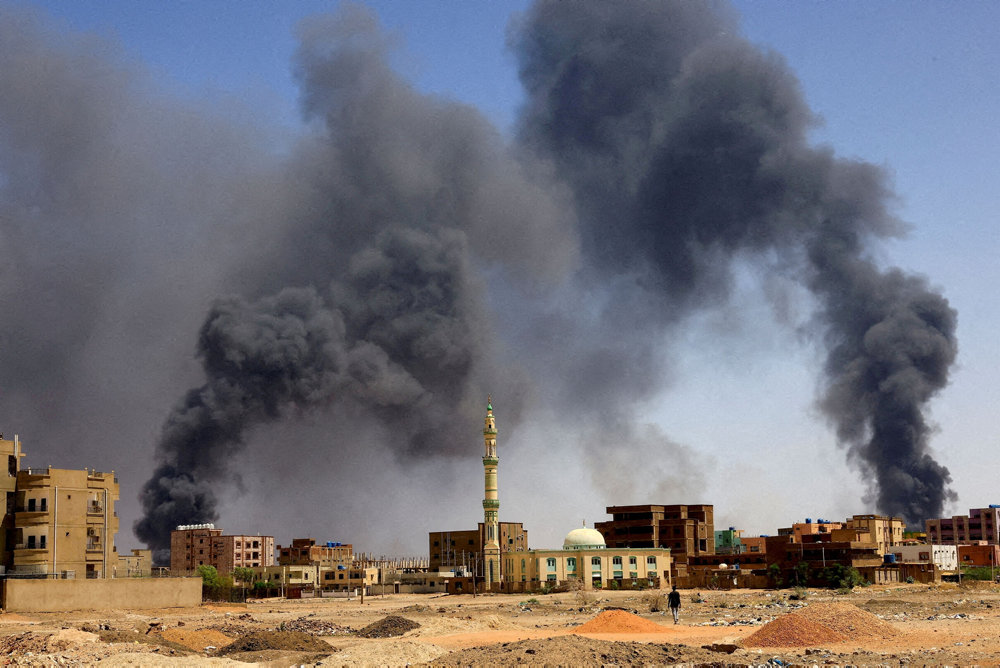 FILE PHOTO: Man walks while smoke rises above buildings after aerial bombardment in Khartoum North