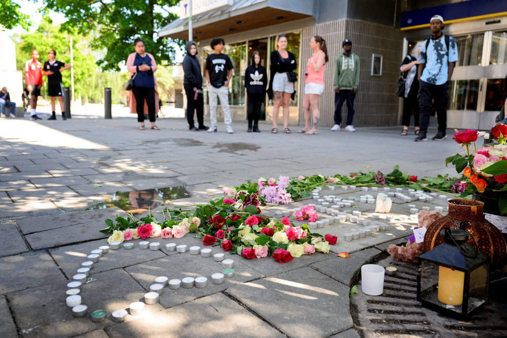 Flowers and candles lay on the ground after a shooting in Stockholm