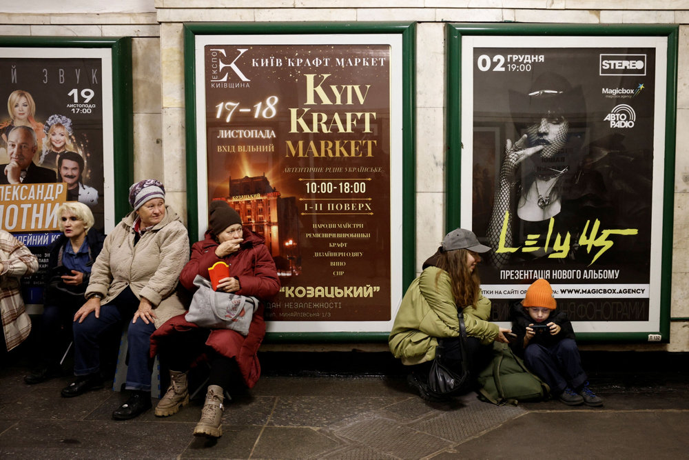 People sit in a metro station to shelter from an air raid in Kyiv
